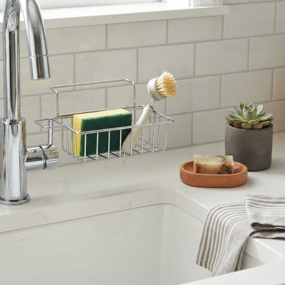 A modern sink caddy organizer holding a sponge and brush on a clean kitchen countertop with terracotta and charcoal decor.